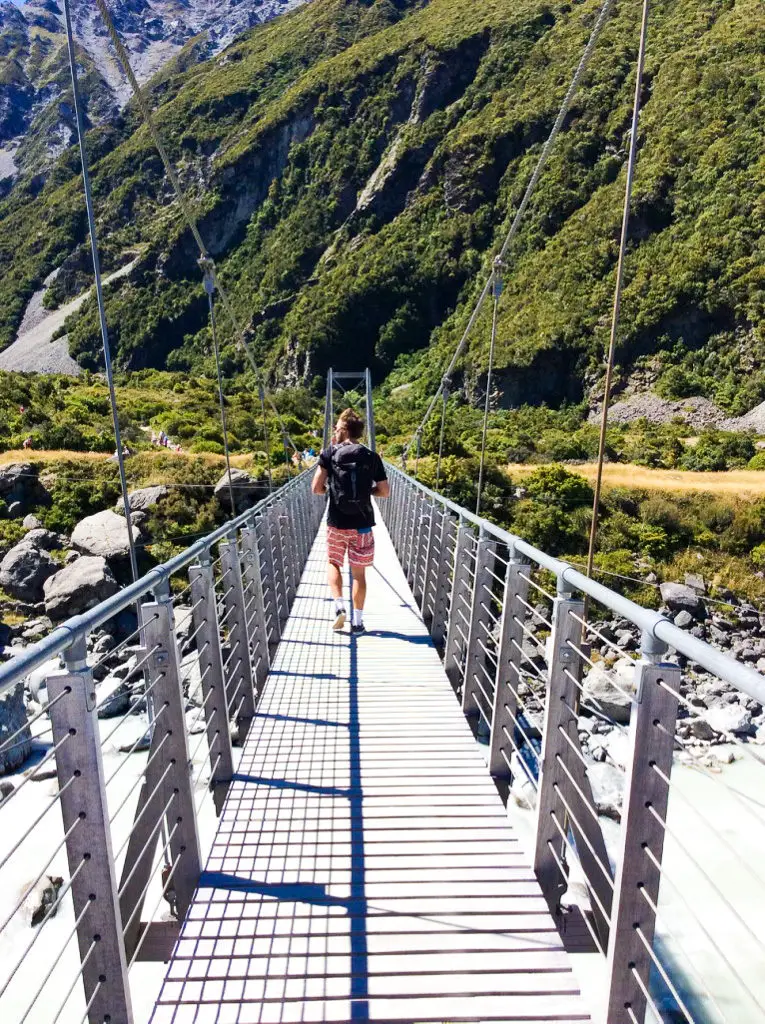 walking over metal suspension bridge in new zealand