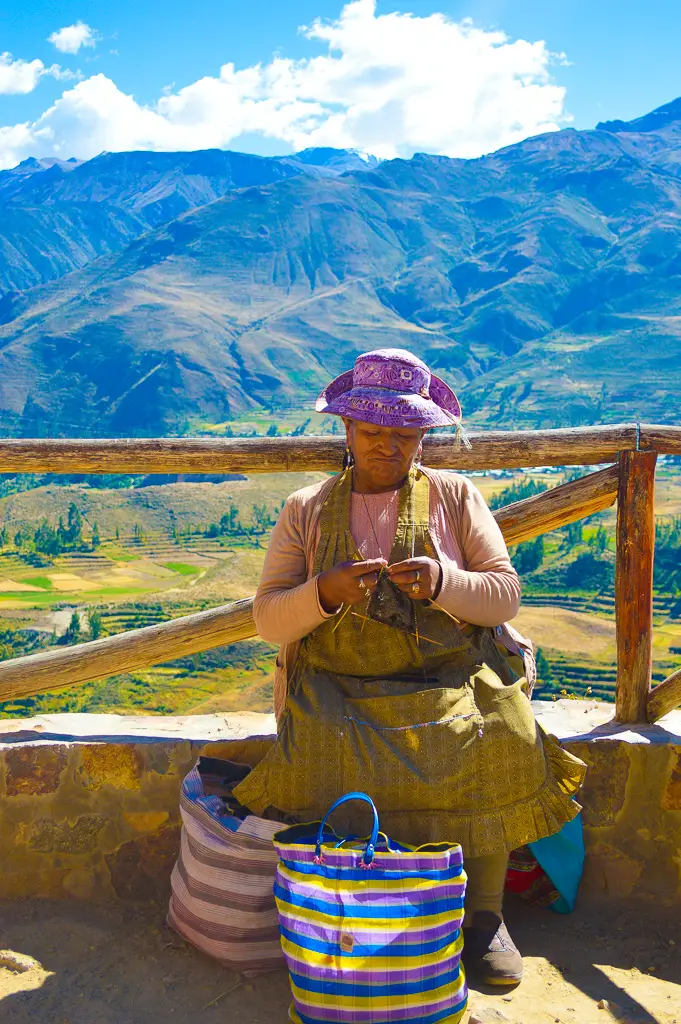 Peruvianwomanknittingwithricefieldbackdropofcolcacanyonmountains
