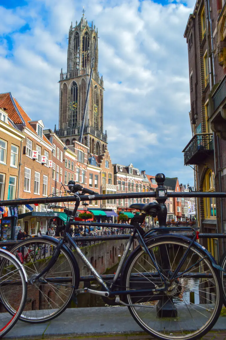 bicycle on bridge with canal and tower in background