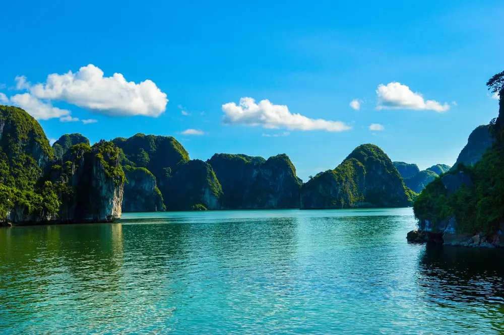 boats on blue water with green limestone turrets