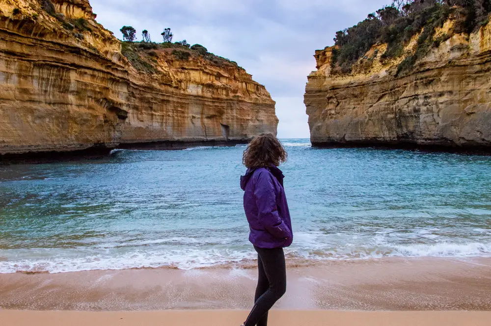 girl in purple waterproof looking out towards the sea and cliffs