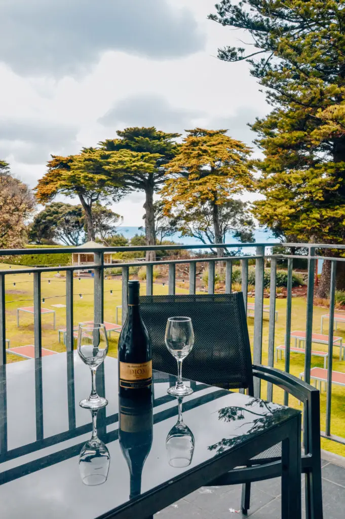 bottle of wine and glasses on black table on balcony with tree background