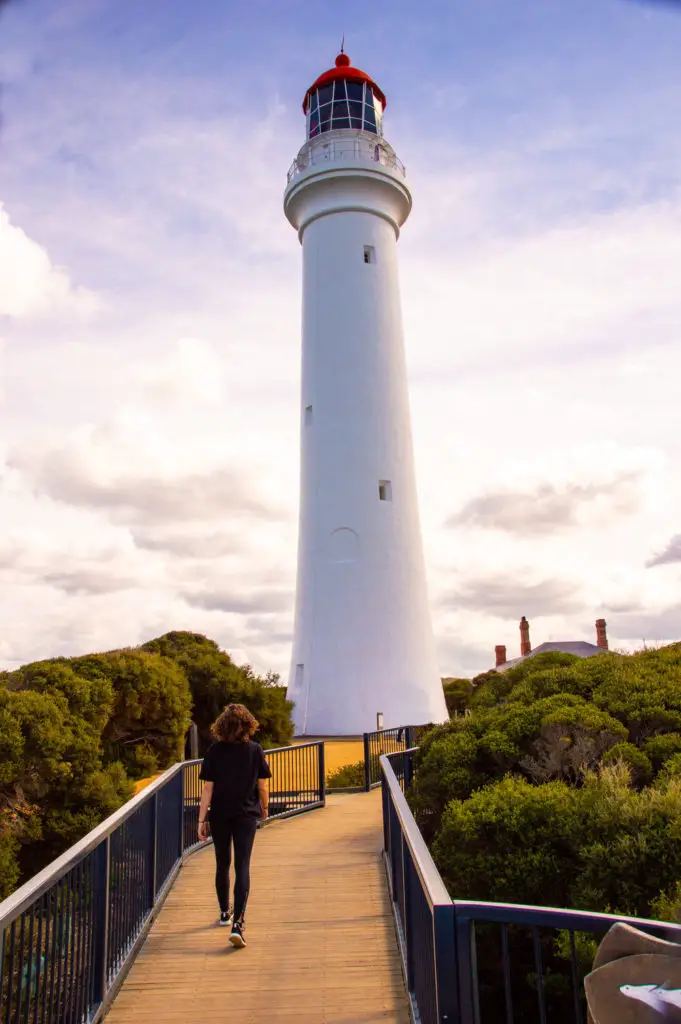 girl walking in front on lighthouse at dusk