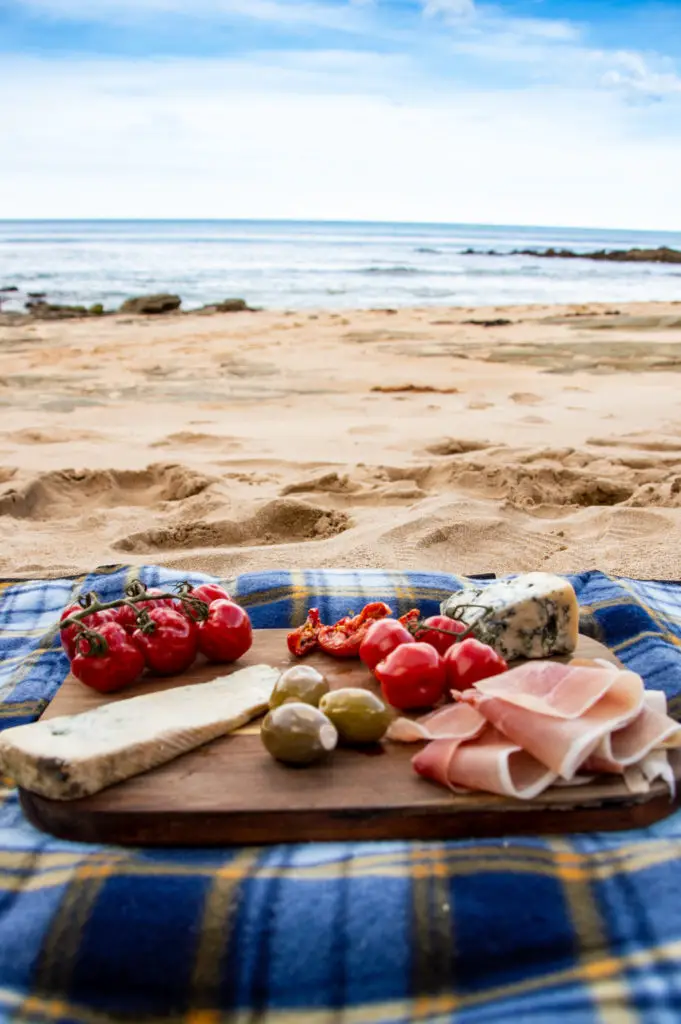 charcuterie platter on a blue mat on the beach