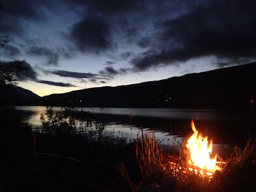 camp fire at nigh beside lake