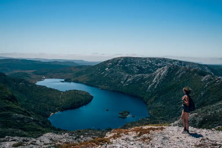 girl standing above deep blue take on mountain in Tasmania Australia