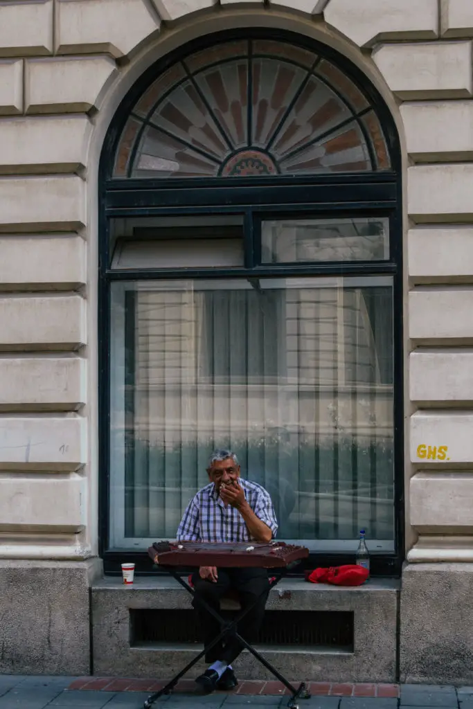 man busking on the street of bucharest in front of large window