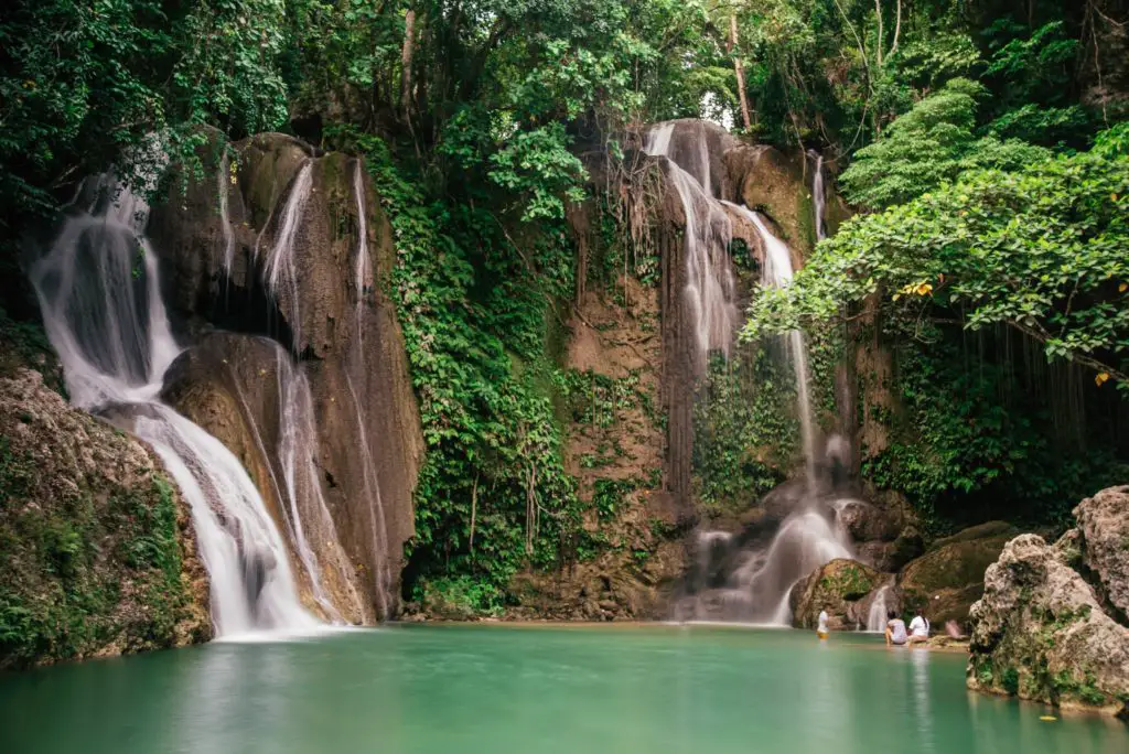 jungle waterfall flowing into pale green pool