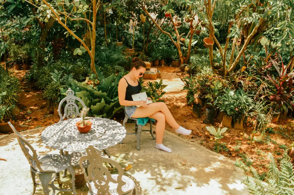 girl sat in jungle garden writing in a journal
