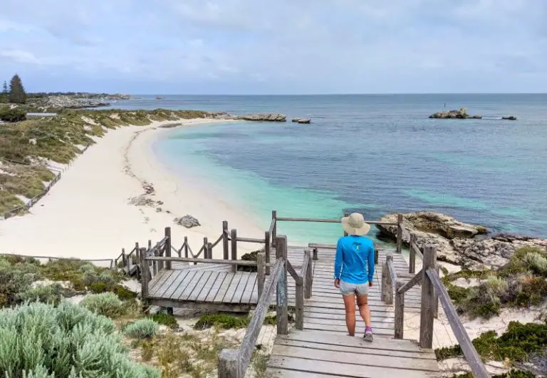 girl walking down wooden boardwalk onto white beach