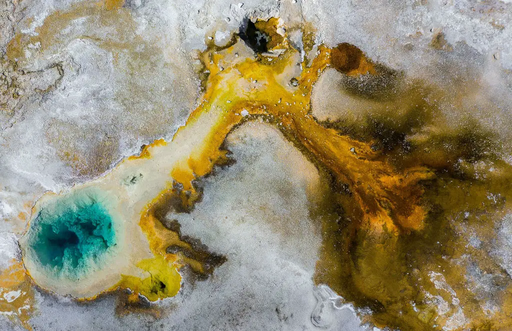 unusual geothermal landscape with blue pool and orange water