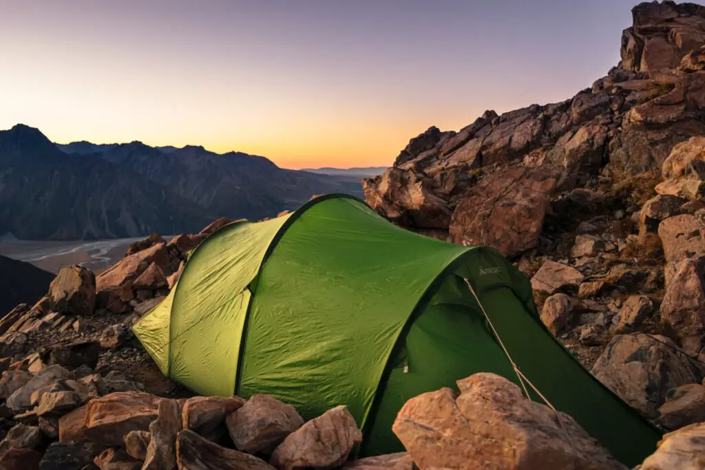 green tent set amongst rocks