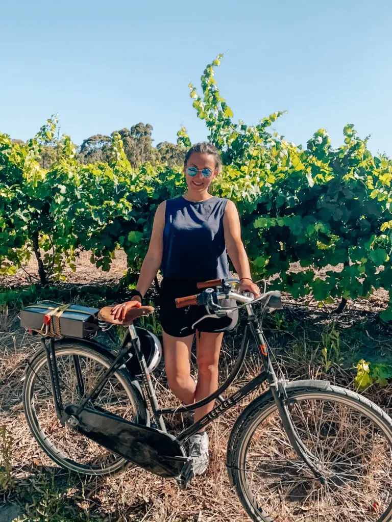 girl with lekker bike in front of grape vines