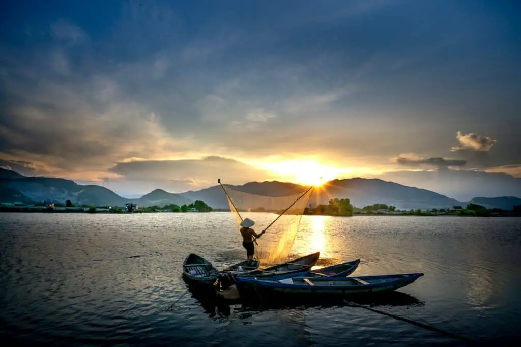 fisherman throwing net at sunset in vietnam