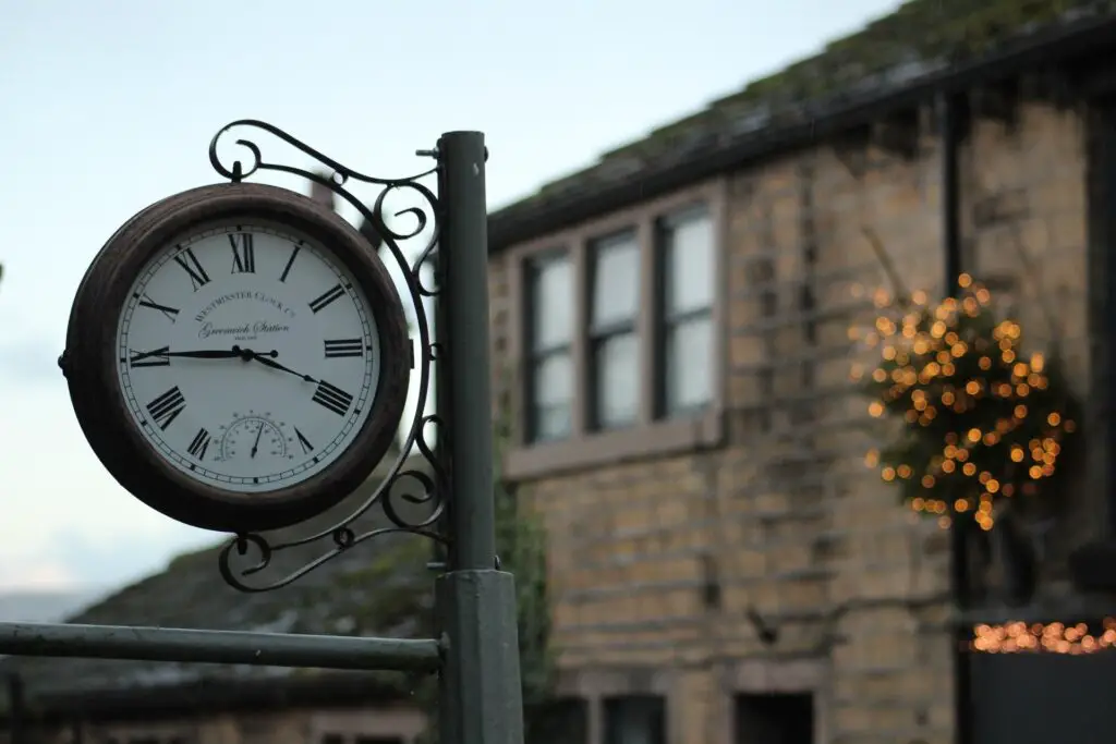 close up of a clock with stone building behind