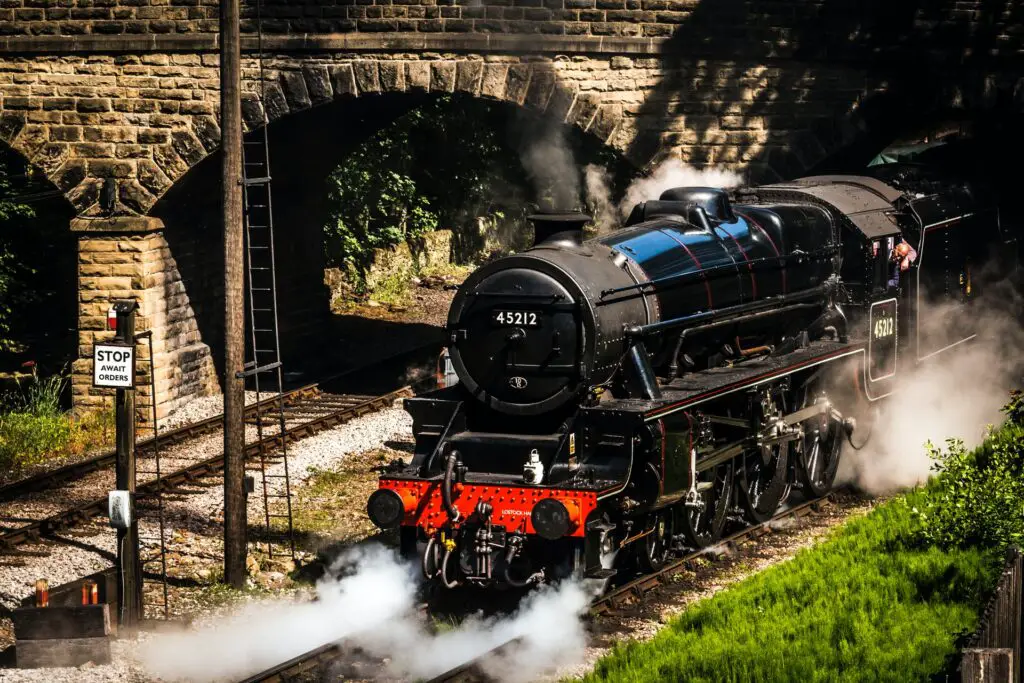 back and red steam train under stone bridge
