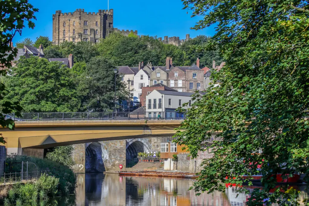 bridge over river with castle and framed by green trees