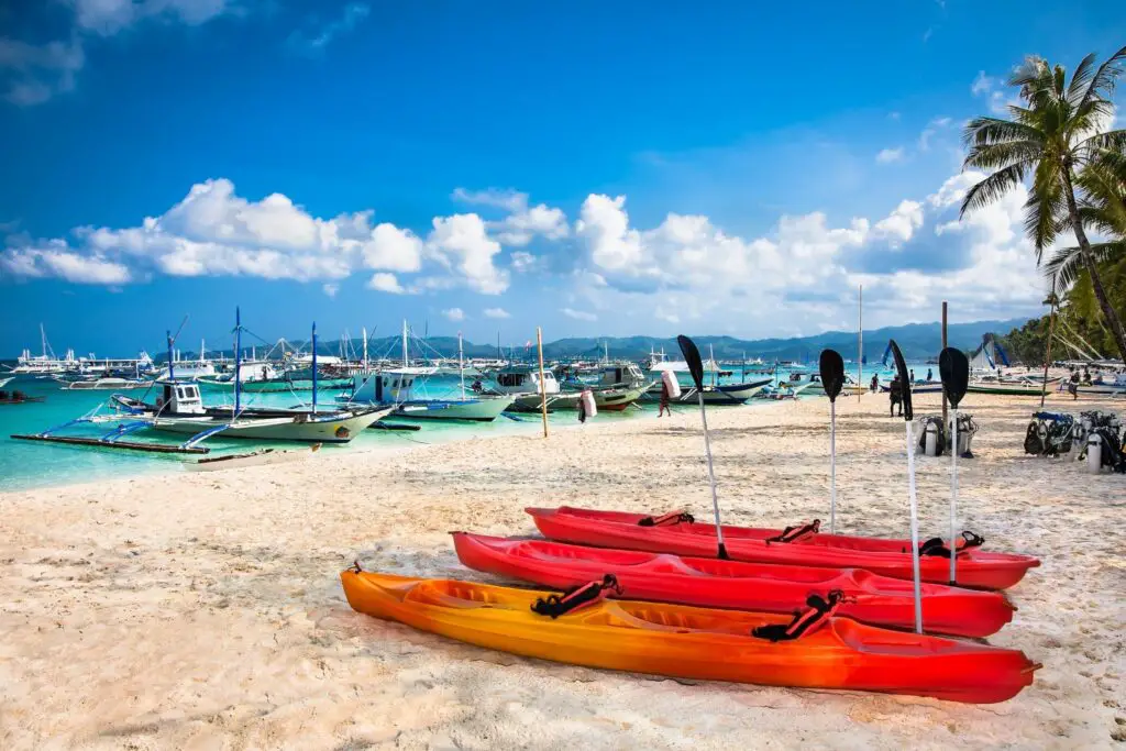 red canoes and boats on the water at Bulabog Beach Boracay