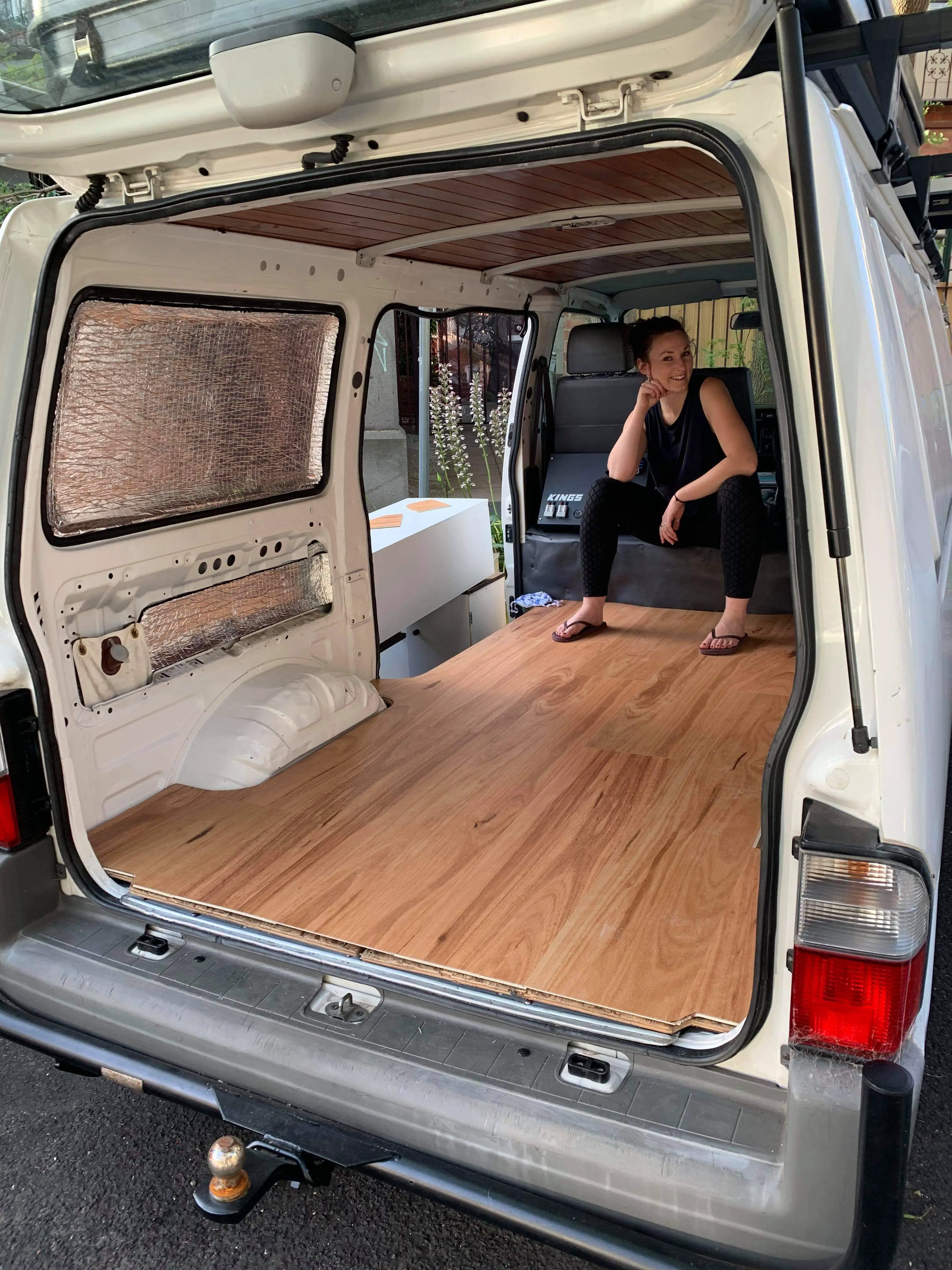 girl sat in shall of a van with wooden floor and insulation 