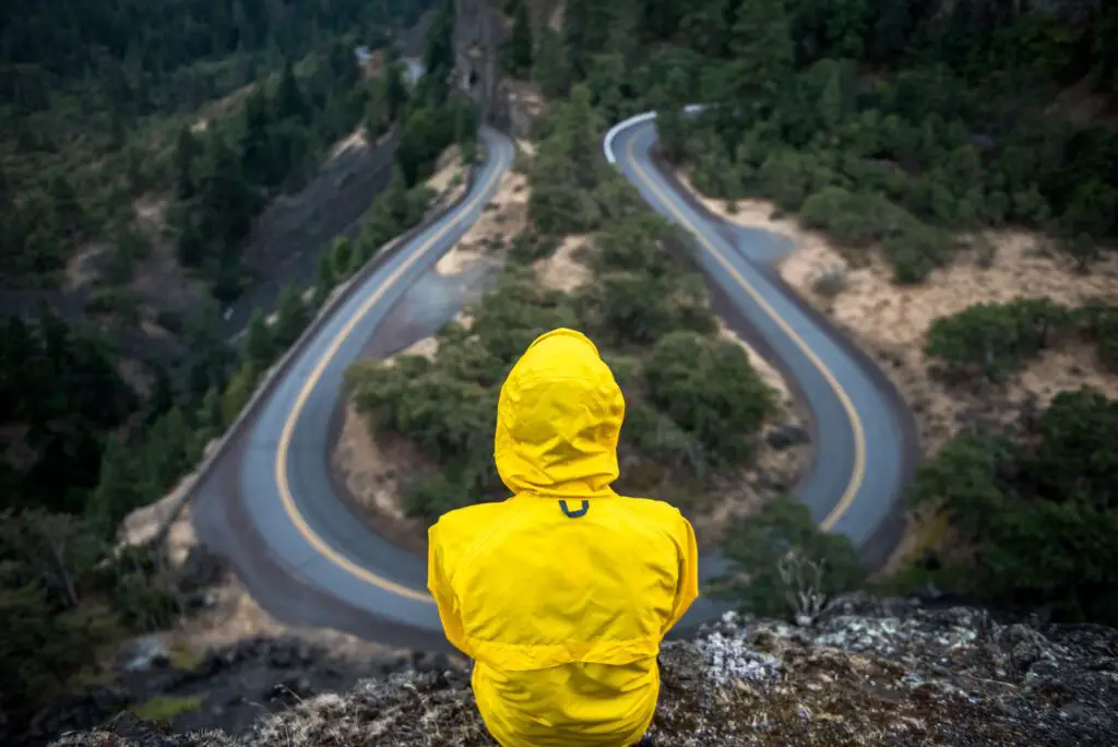 person in yellow raincoat in front of a road